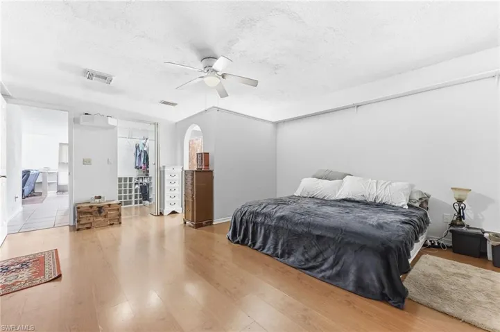 Main Bedroom with a textured ceiling, light wood-style floors, a ceiling fan, and arched walkways