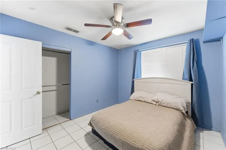 Bedroom with ceiling fan, light tile patterned floors, and a closet