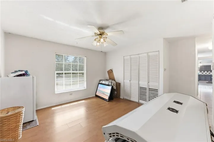 Den with ceiling fan and light wood-style flooring