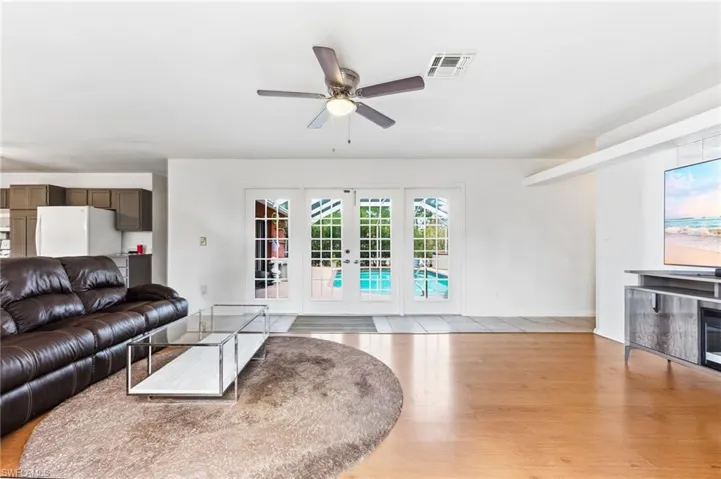 Living room featuring french doors, a ceiling fan, and light wood-style flooring