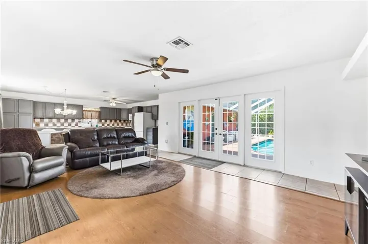Living area featuring french doors, light wood-style flooring, ceiling fan, and suspended lighting