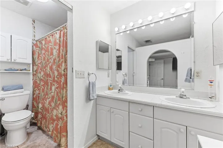 Bathroom with a shower with shower curtain, double vanity, and a textured wall