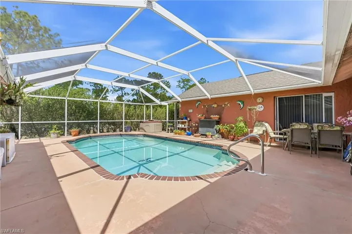 Swimming pool featuring glass enclosure, a sunroom, a patio area, and outdoor dining area