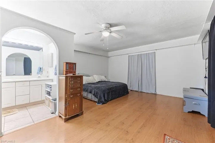 Main bedroom with a ceiling fan, light wood-style flooring, a textured ceiling, and ensuite bath
