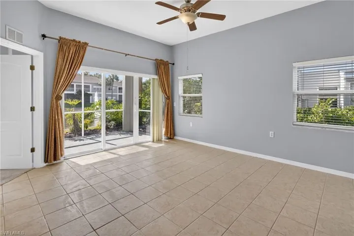 Spacious interior featuring tile flooring, vaulted ceilings, a ceiling fan, and multiple windows providing natural light