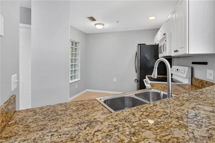 Kitchen featuring a double basin stainless steel sink with a high-arch faucet, granite countertops, white cabinetry, and recessed lighting