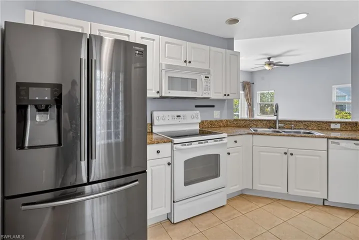 Kitchen featuring white cabinetry, granite-finish countertops, and tile flooring