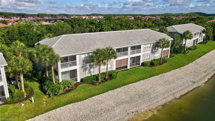 Two-story multi-unit dwelling with screened balconies, light gray exterior siding, and a gray tile roof