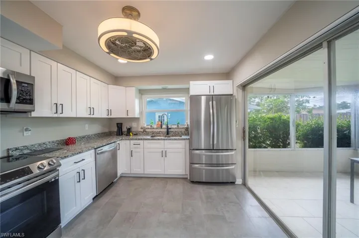 Kitchen with appliances with stainless steel finishes, plenty of natural light, white cabinets, and recessed lighting