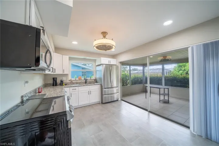 Kitchen with freestanding refrigerator, white cabinetry, plenty of natural light, and recessed lighting