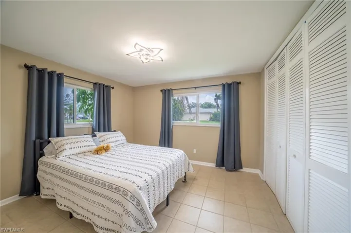 Bedroom with multiple windows, light tile patterned floors, and a closet