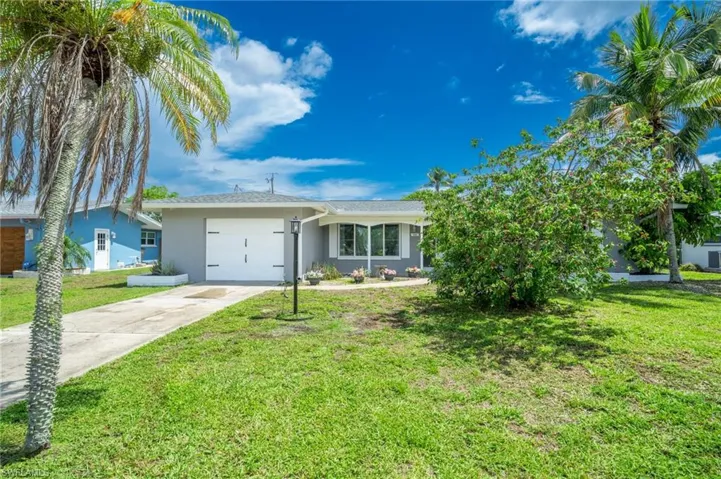 Ranch-style home with stucco siding, a garage, driveway, and a front yard