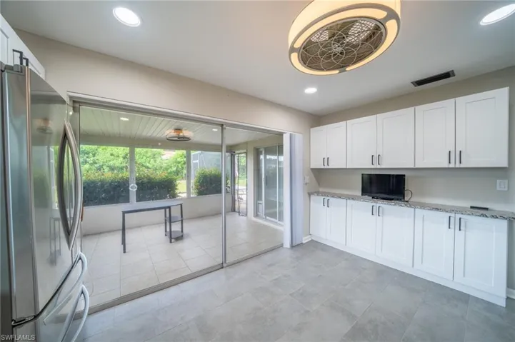 Kitchen featuring freestanding refrigerator, white cabinetry, light stone countertops, and recessed lighting