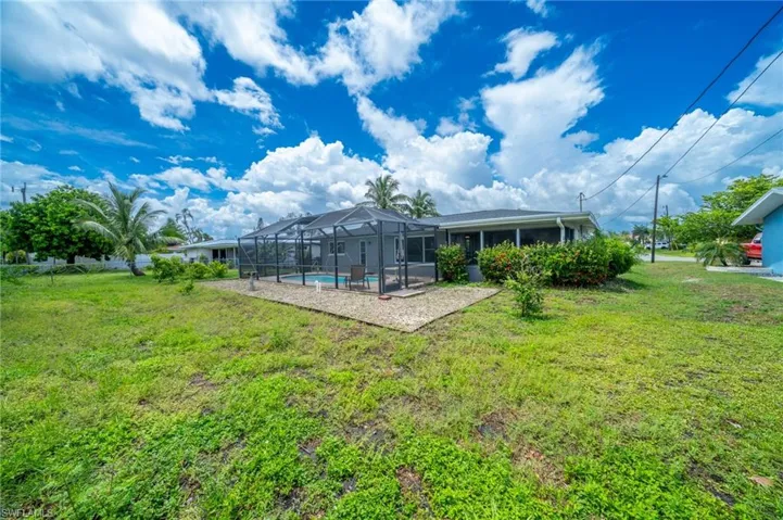 Rear view of house featuring an outdoor pool, a yard, glass enclosure, and a patio