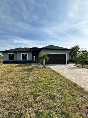 View of front of house with a front lawn, decorative driveway, stucco siding, and an attached garage
