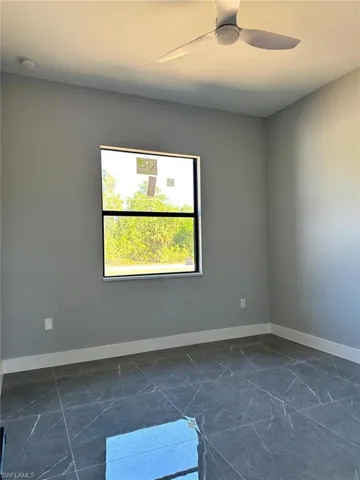 Empty room featuring baseboards, marble finish floor, and ceiling fan