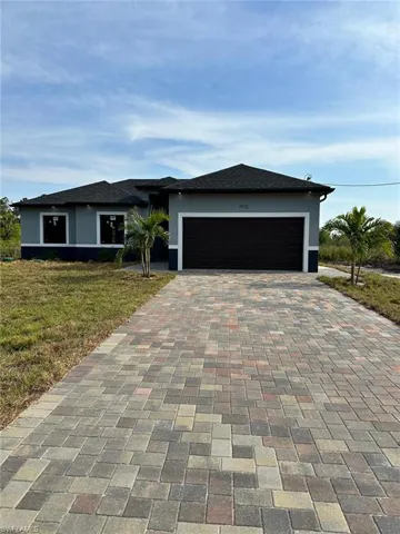 View of front facade with stucco siding, an attached garage, and decorative driveway