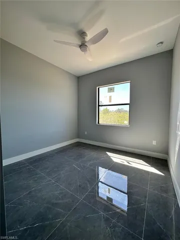 Spare room with baseboards, marble finish floor, and a ceiling fan