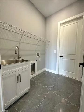 Washroom featuring marble finish floor, a sink, hookup for an electric dryer, and cabinet space