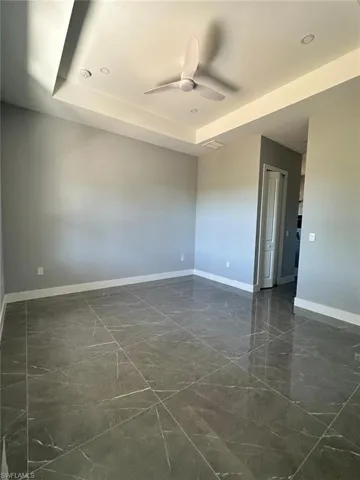 Empty room with recessed lighting, baseboards, marble finish floor, a raised ceiling, and ceiling fan