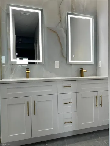 Bathroom featuring marble finish floor, vanity, visible vents, and decorative backsplash