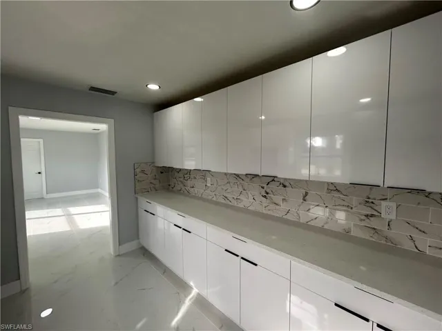Kitchen featuring visible vents, marble finish floor, light countertops, decorative backsplash, and modern cabinets