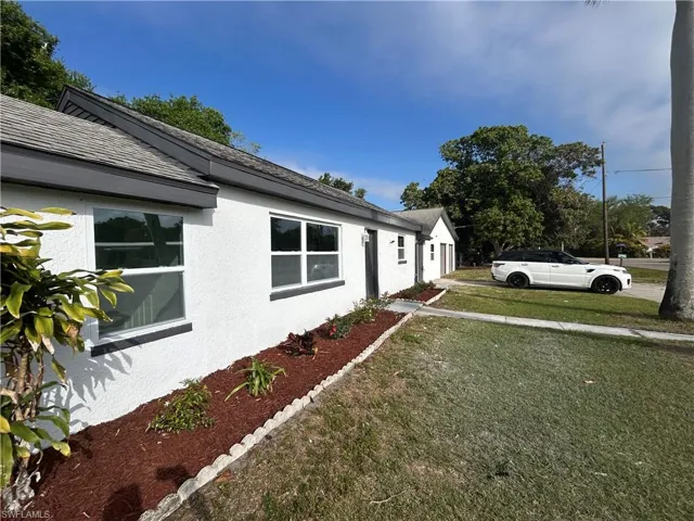 View of property exterior with roof with shingles, a lawn, and stucco siding