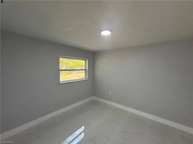 Empty room featuring a textured ceiling, marble finish floor, and baseboards