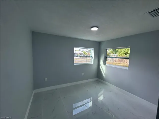 Spare room with marble finish floor, baseboards, and a textured ceiling