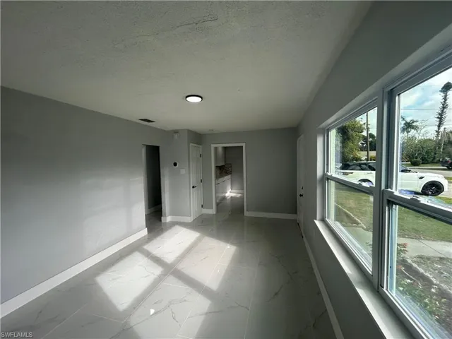 Unfurnished room featuring marble finish floor, visible vents, a textured ceiling, and baseboards