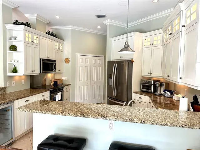 Features include stainless steel, granite, a wine fridge, and accent lighting.