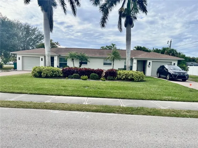 Single story home featuring an attached garage, a front yard, driveway, and stucco siding