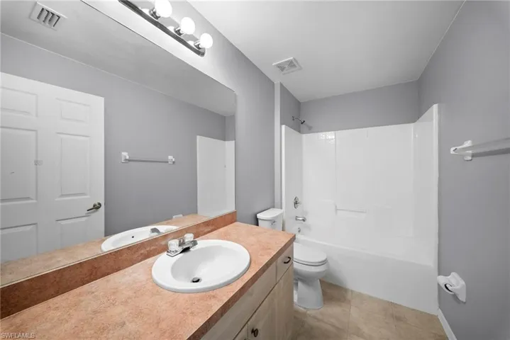 Bathroom with vanity, washtub / shower combination, and light tile patterned floors