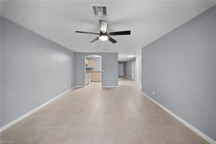 Unfurnished living room featuring arched walkways, ceiling fan, and light tile patterned floors