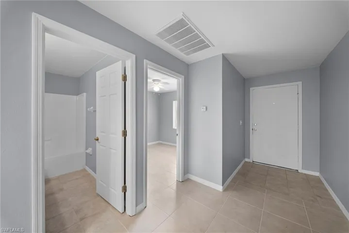 Hall with baseboards and light tile patterned floors