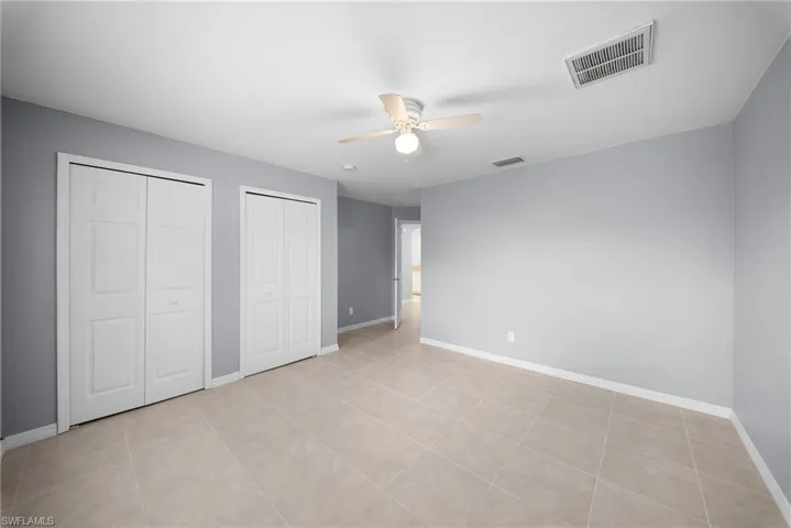 Unfurnished bedroom featuring multiple closets and a ceiling fan