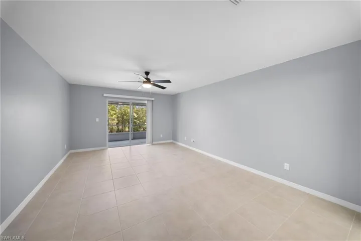 Empty room with ceiling fan and light tile patterned floors