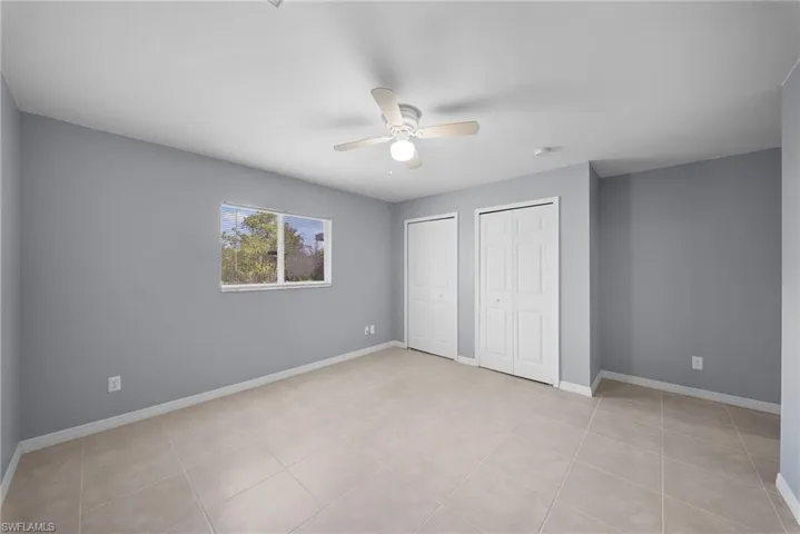 Unfurnished bedroom with two closets, a ceiling fan, and light tile patterned floors