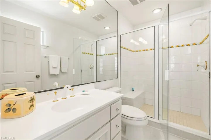 Bathroom featuring toilet, vanity, a stall shower, tile patterned floors, and recessed lighting