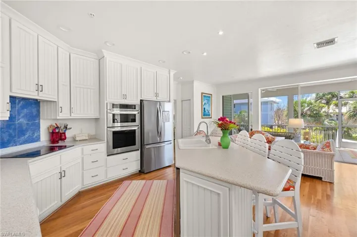 Kitchen featuring stainless steel appliances, a sink, light wood-style floors, light countertops, and white cabinetry