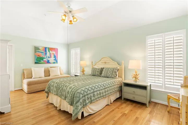Bedroom featuring light wood-style floors, baseboards, ceiling fan, and lofted ceiling