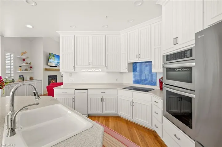 Kitchen featuring fridge, a sink, stainless steel double oven, black electric cooktop, and light wood-style flooring