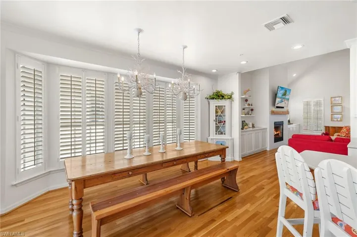 Dining space with a chandelier, light wood-type flooring, a warm lit fireplace, recessed lighting, and baseboards