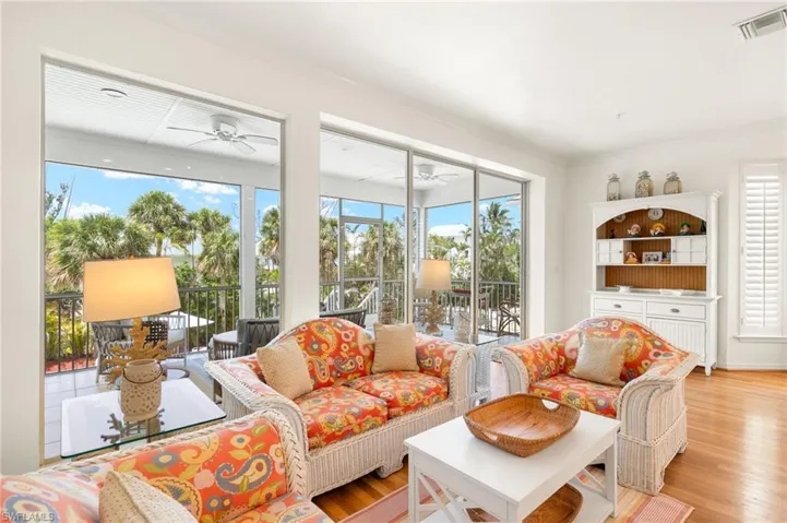 Living area with wood finished floors, ceiling fan, and ornamental molding