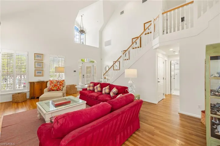 Living area featuring high vaulted ceiling, stairway, wood finished floors, and baseboards