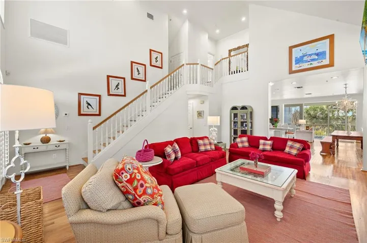 Living area with stairway, wood finished floors, a towering ceiling, and recessed lighting