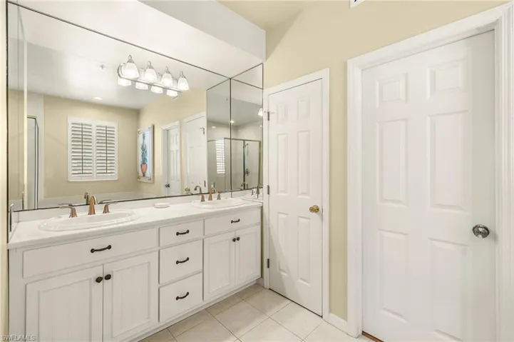 Bathroom with tile patterned flooring, double vanity, and a shower stall