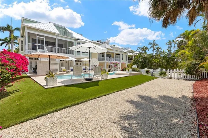 Rear view of house with a sunroom, an outdoor pool, a patio area, metal roof, and stairs