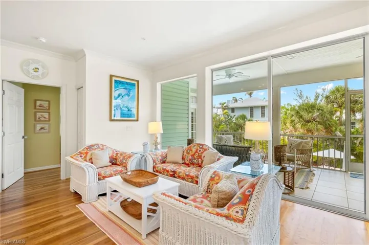 Living area featuring wood finished floors, crown molding, ceiling fan, and baseboards