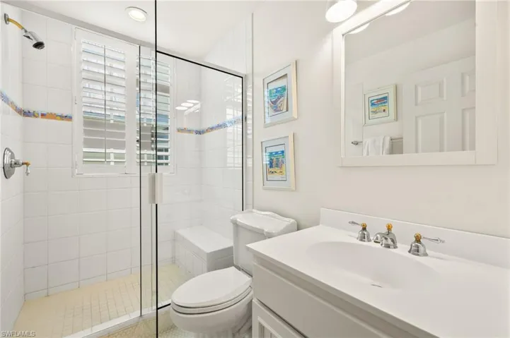 Bathroom featuring a stall shower, vanity, and toilet